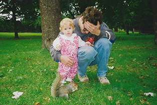 man and child watching squirrel in park